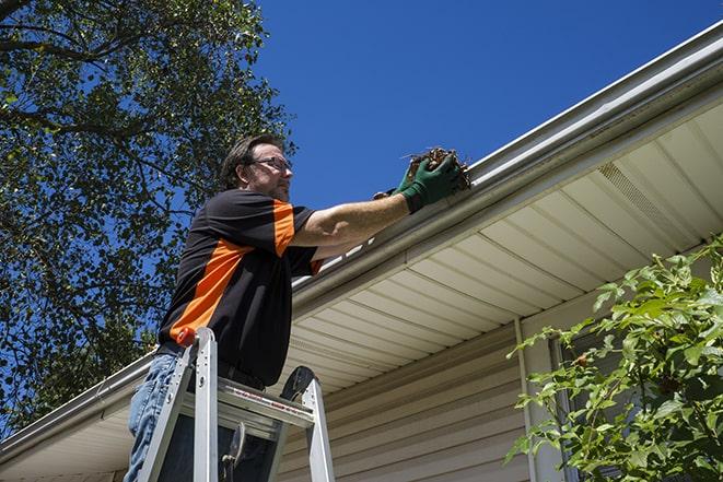 a gutter repair specialist working on a broken downspout in Brentwood MO